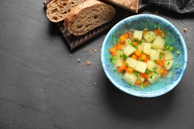 Photo of Bowl of fresh homemade vegetable soup on black background, top view. Space for text