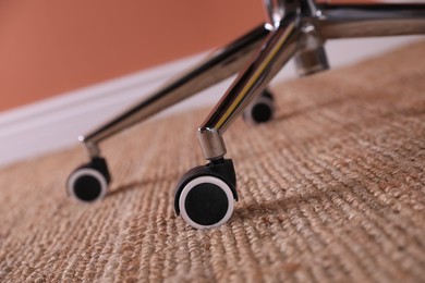 Photo of Modern office chair with wheels on floor, closeup
