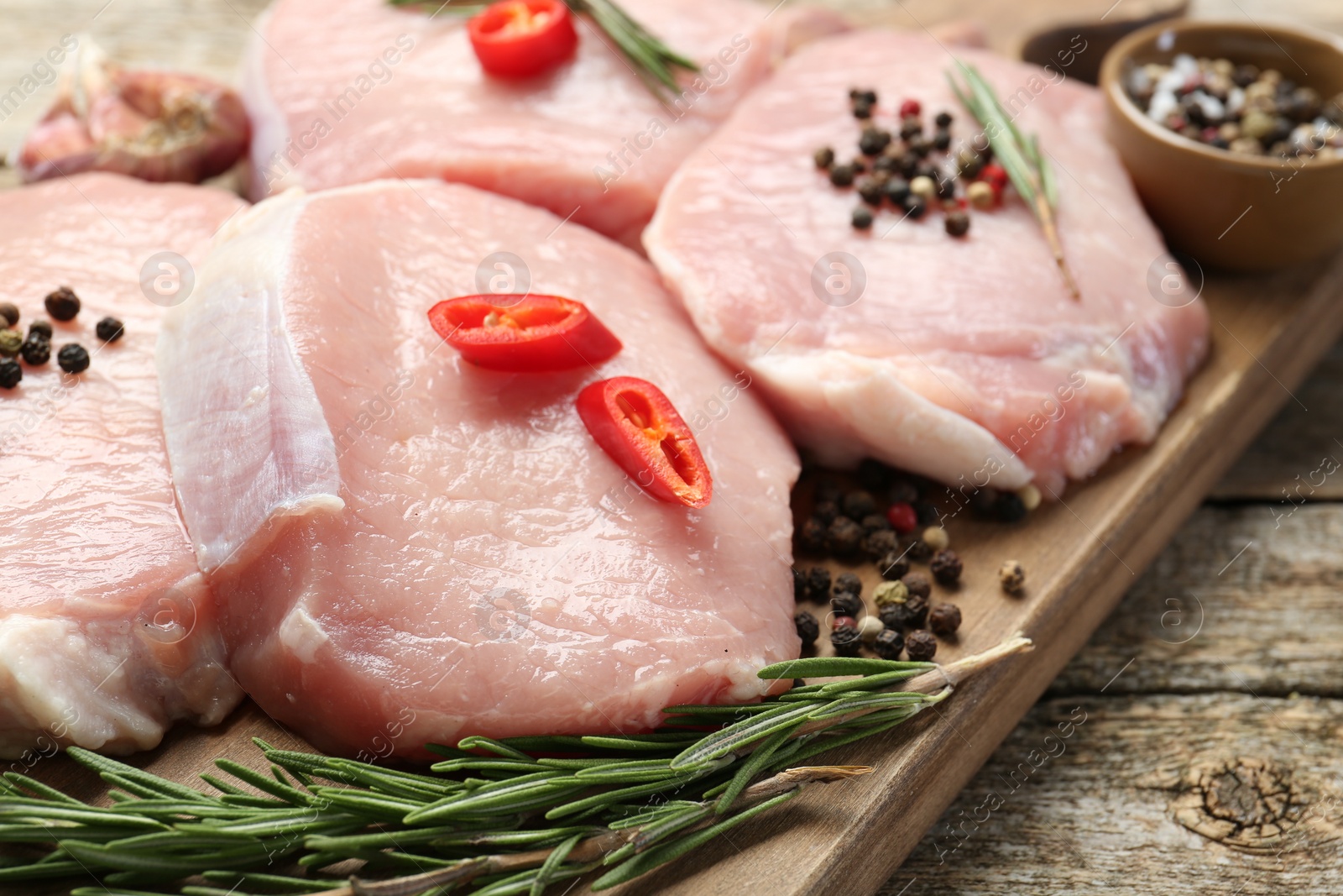 Photo of Pieces of raw pork meat and spices on wooden table, closeup