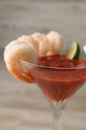 Tasty shrimp cocktail with sauce in glass on table, closeup