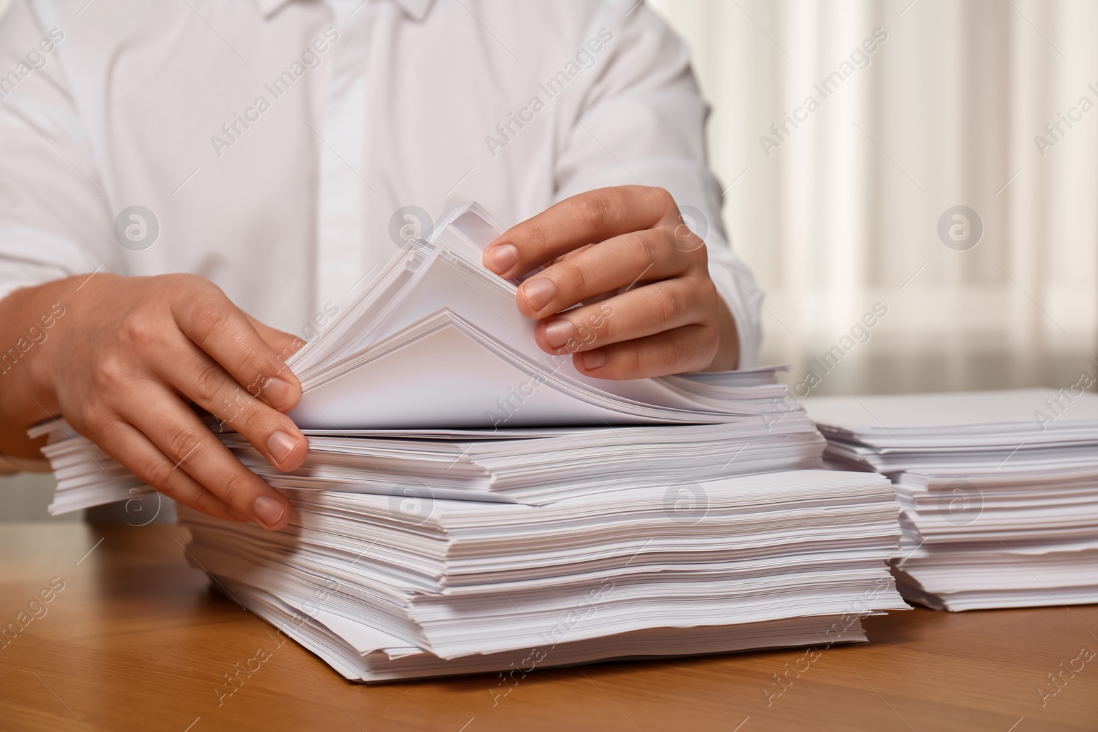 Photo of Man stacking documents at table in office, closeup