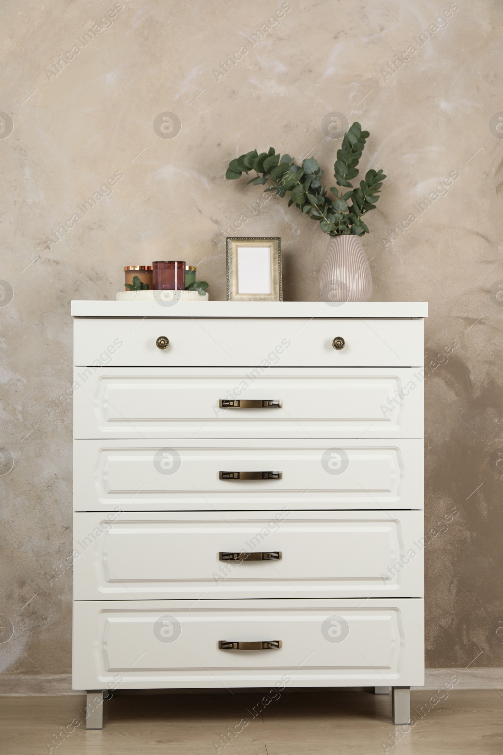 Photo of Modern chest of drawers with decor near beige wall