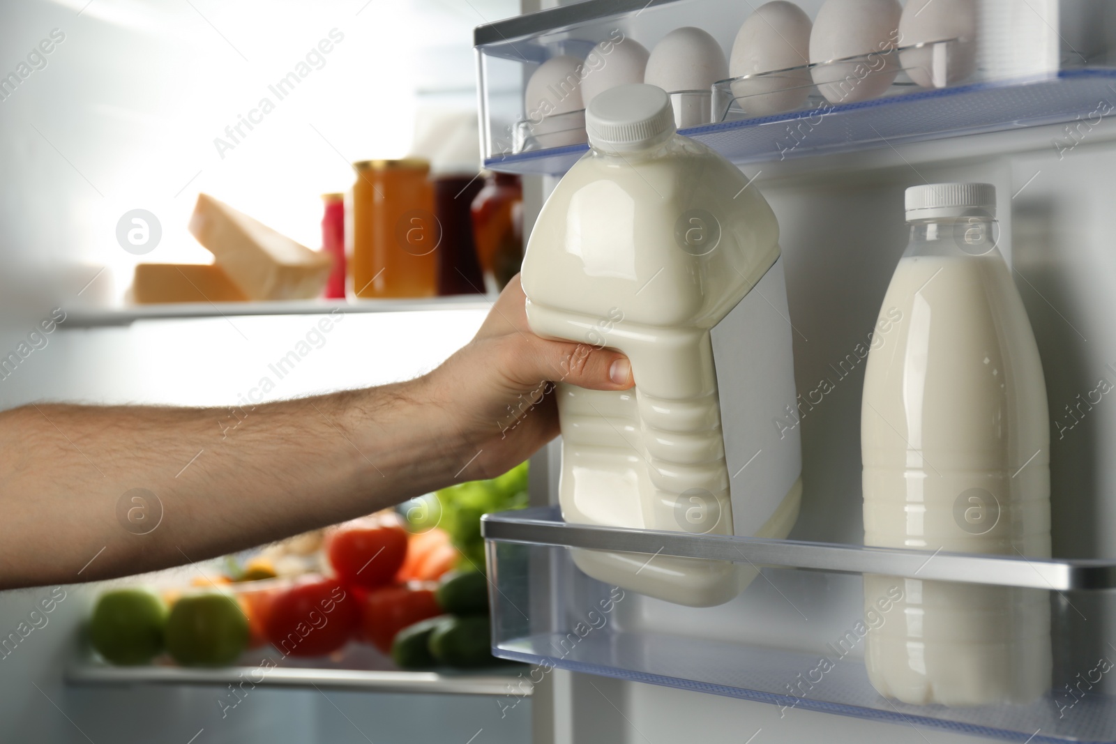 Photo of Man taking gallon of milk from refrigerator, closeup