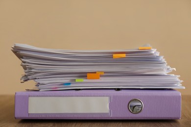 Stack of documents and office folder on wooden table against brown background