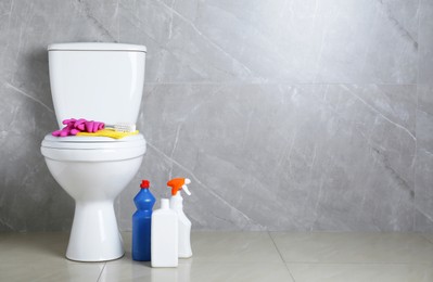 Photo of Toilet bowl and different cleaning supplies indoors, space for text