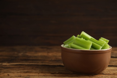 Cut celery in bowl on wooden table. Space for text