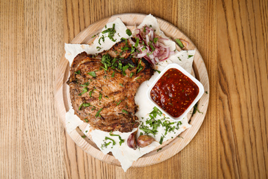 Photo of Delicious grilled pork chop served on wooden table, top view