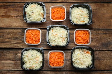 Plastic containers with tasty vegetable salads on wooden table, flat lay. Food delivery service