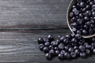 Photo of Ripe bilberries on dark wooden table, closeup. Space for text