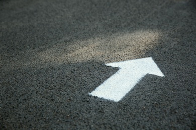 Photo of White arrow painted on asphalt. Space for text