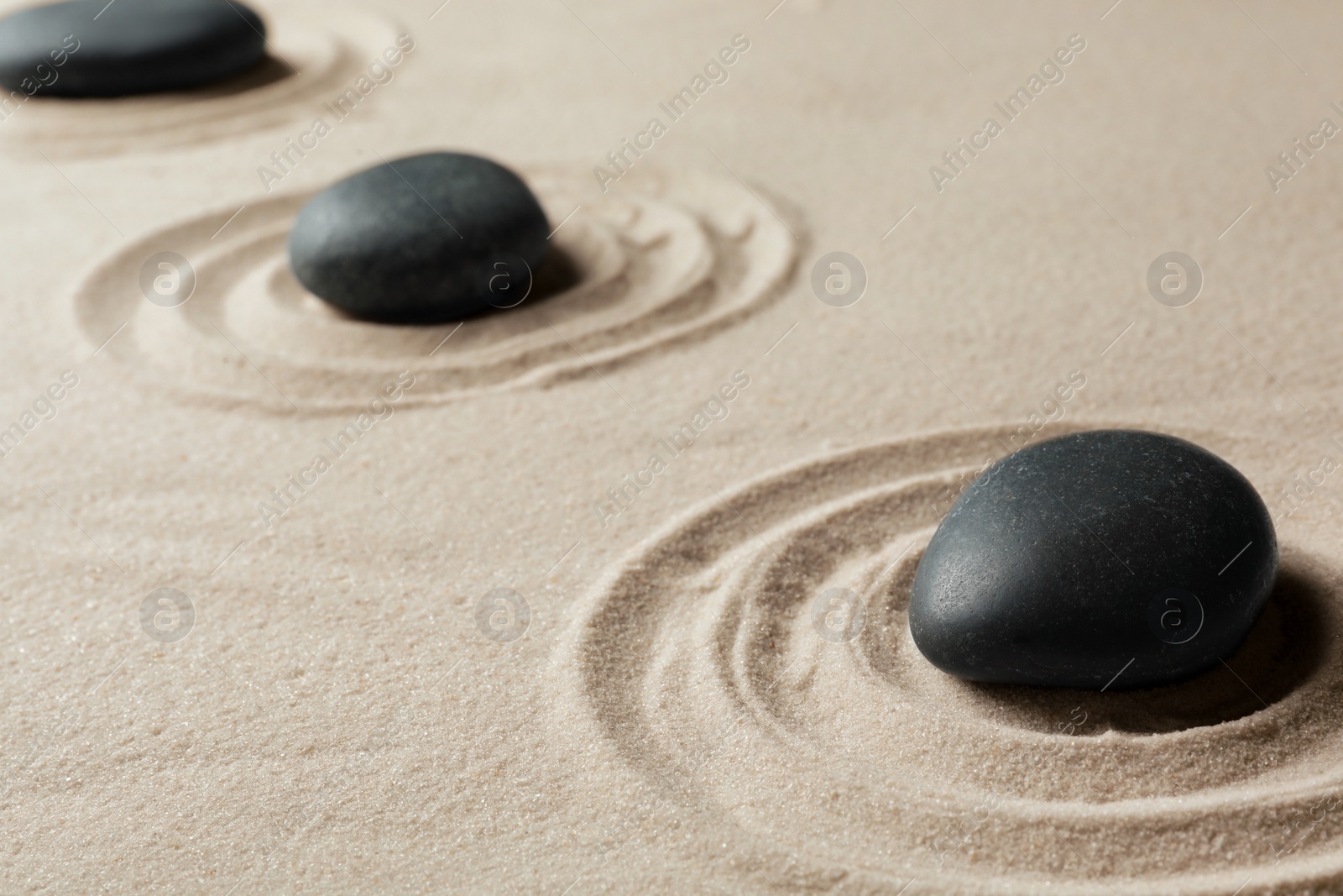 Photo of Zen garden stones on sand with pattern. Meditation and harmony