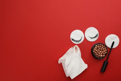 Dirty cotton pads, wet wipe and cosmetic products on red background, flat lay. Space for text