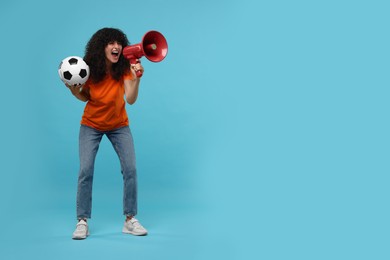 Photo of Happy fan with soccer ball using megaphone on light blue background, space for text
