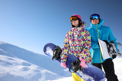 Photo of Couple with snowboards on hill, low angle view. Winter vacation