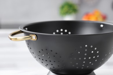 Photo of One black colander on blurred background, closeup