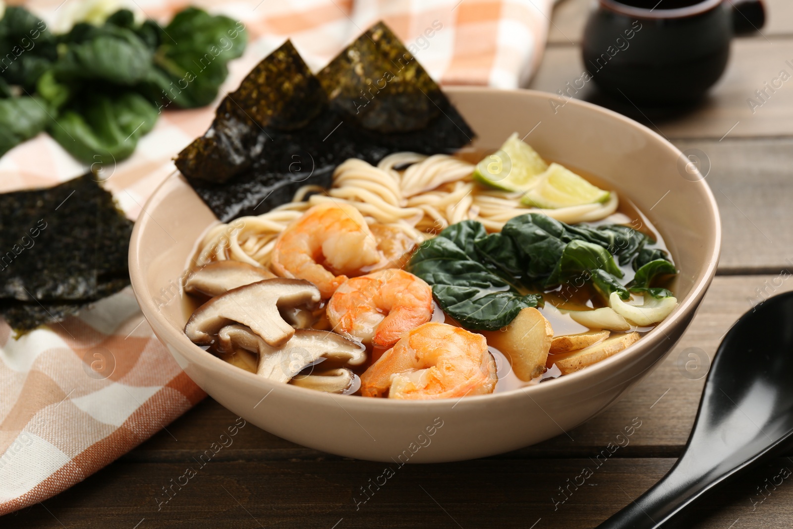 Photo of Delicious ramen with shrimps and mushrooms in bowl served on wooden table, closeup. Noodle soup