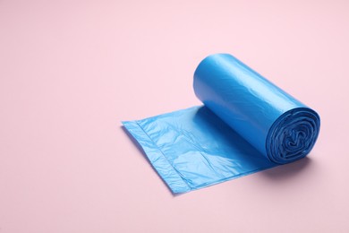 Photo of Roll of light blue garbage bags on pink background. Space for text