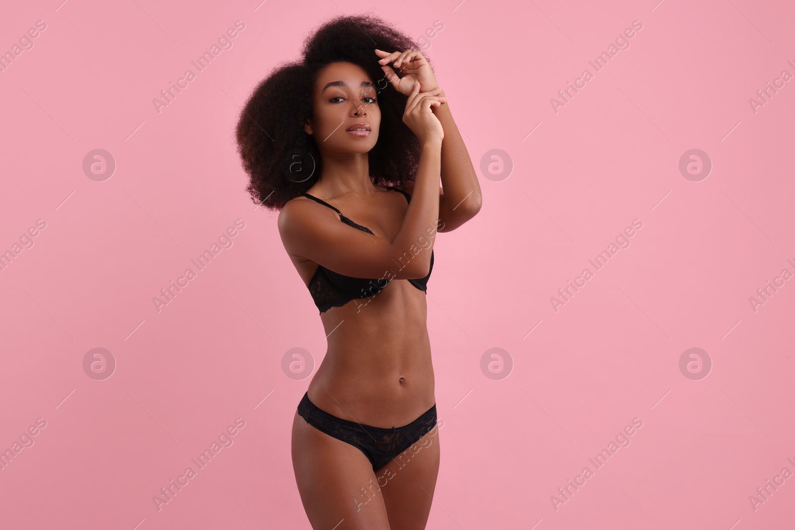 Photo of Beautiful woman in elegant black underwear on pink background