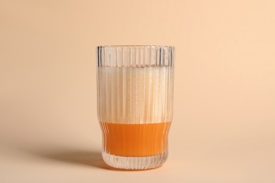 Photo of Glass of delicious eggnog on beige background