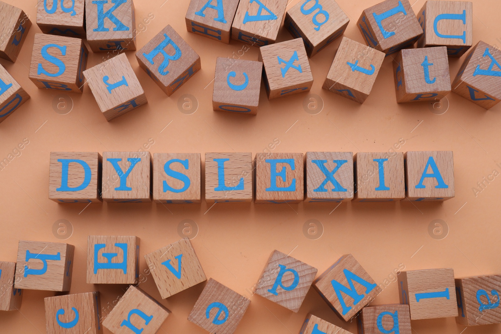 Photo of Wooden cubes with word Dyslexia on pale orange background, flat lay