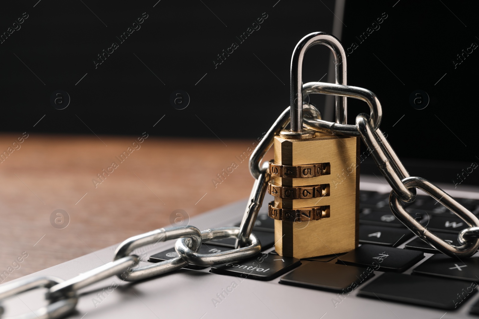 Photo of Cyber security. Laptop with padlock and chain on table, closeup