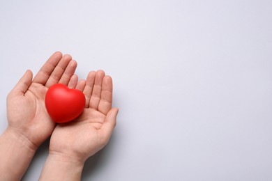 Photo of Man holding red decorative heart on light grey background, top view and space for text. Cardiology concept