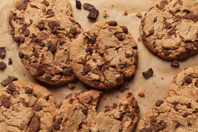 Photo of Delicious chocolate chip cookies on parchment paper, flat lay