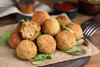 Photo of Delicious falafel balls with herbs on wooden table, closeup