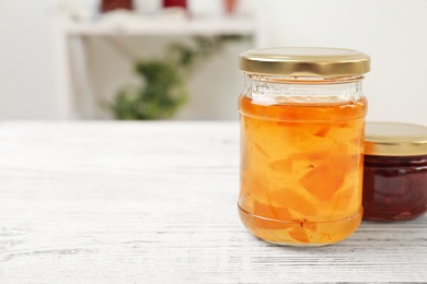 Photo of Two jars with tasty sweet jam on wooden table