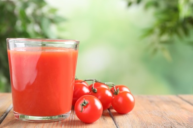 Photo of Delicious tomato juice and vegetables on wooden table. Space for text