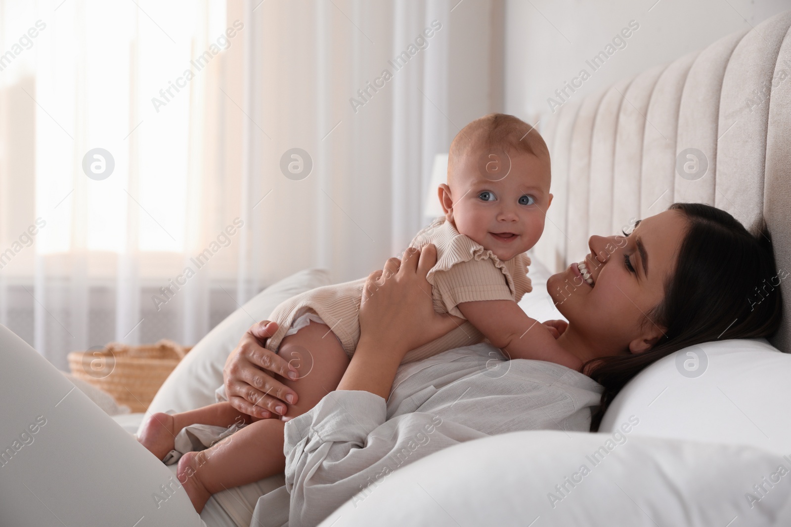 Photo of Young woman with her little baby on bed at home