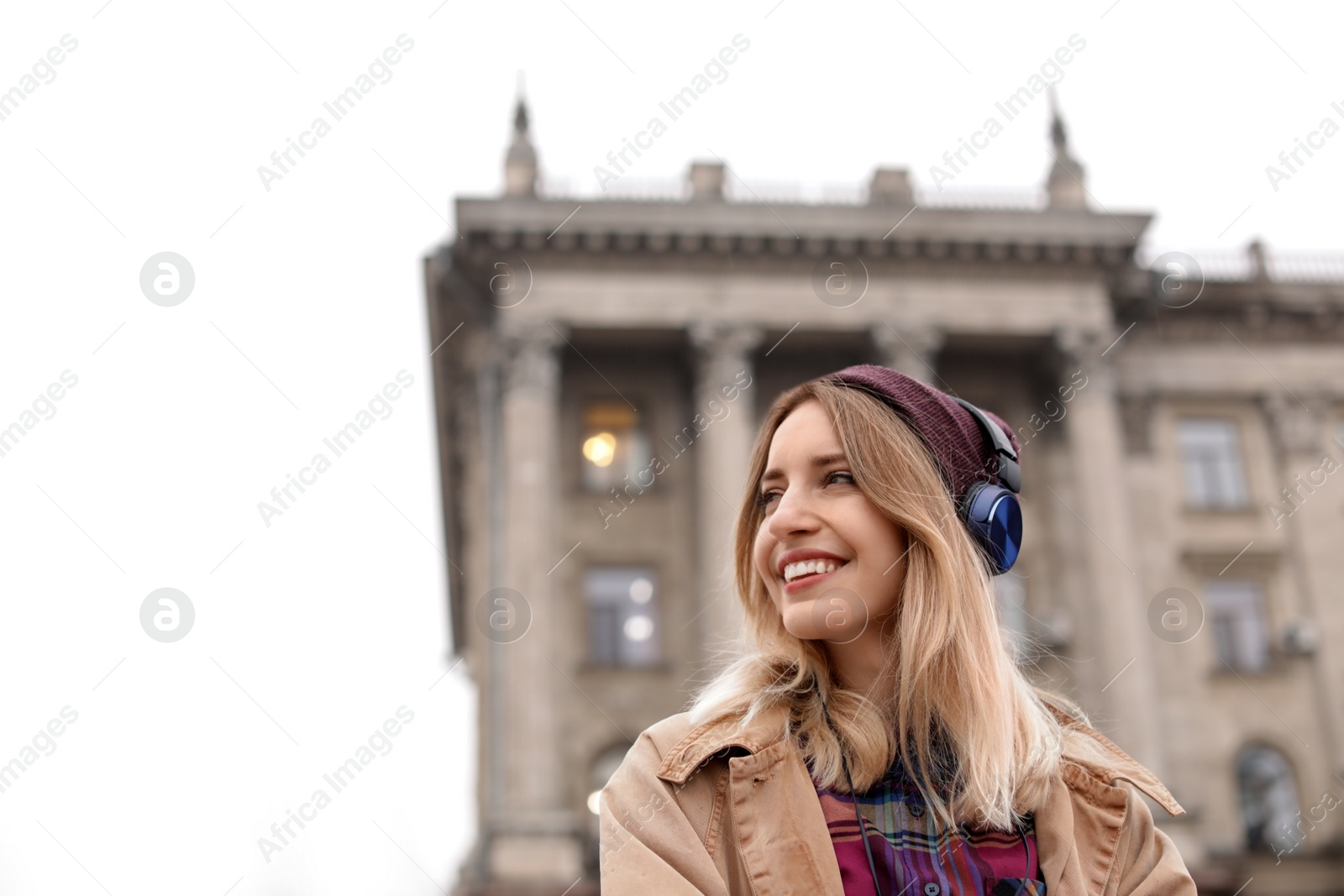 Photo of Young woman with headphones listening to music outdoors. Space for text