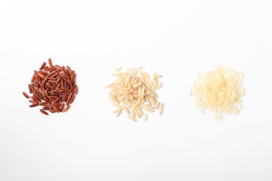 Different types of uncooked rice on white background, top view