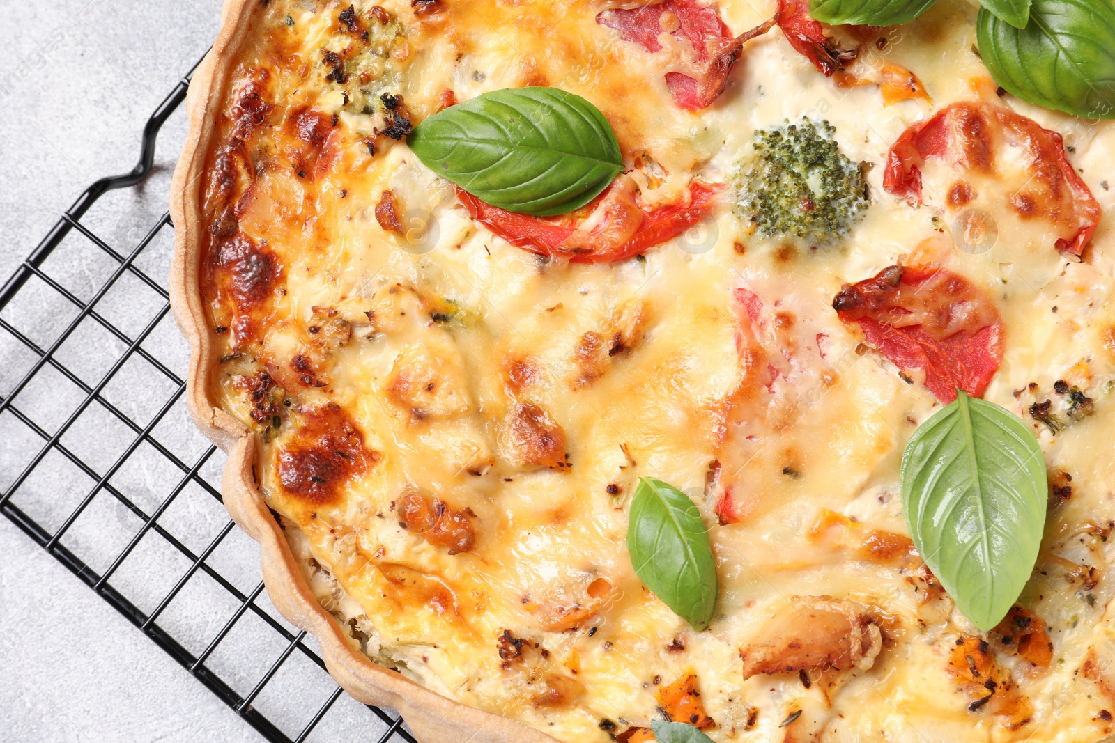 Photo of Tasty quiche with tomatoes, basil and cheese on light textured table, top view