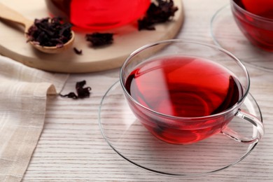 Photo of Fresh hibiscus tea and dry flower leaves on wooden table, closeup