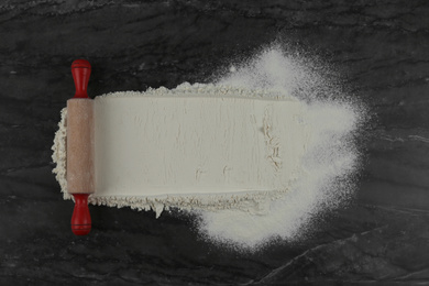 Photo of Flour and rolling pin on grey marble table, flat lay with space for text