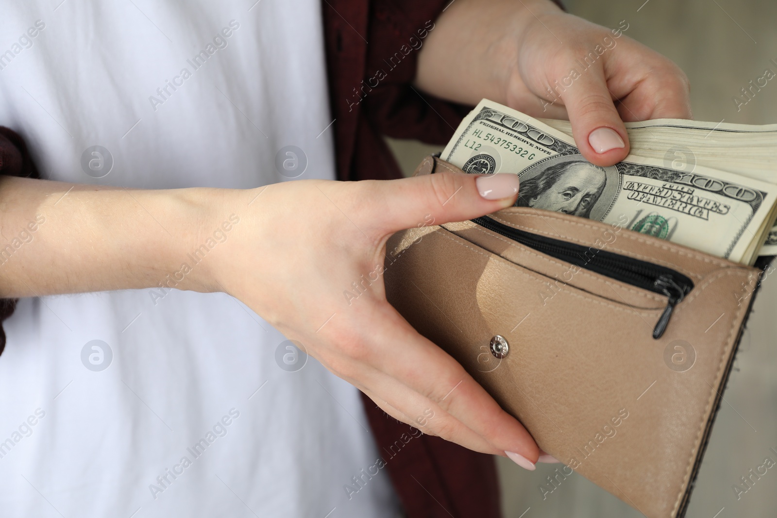 Photo of Money exchange. Woman putting dollar banknotes into wallet on blurred background, closeup