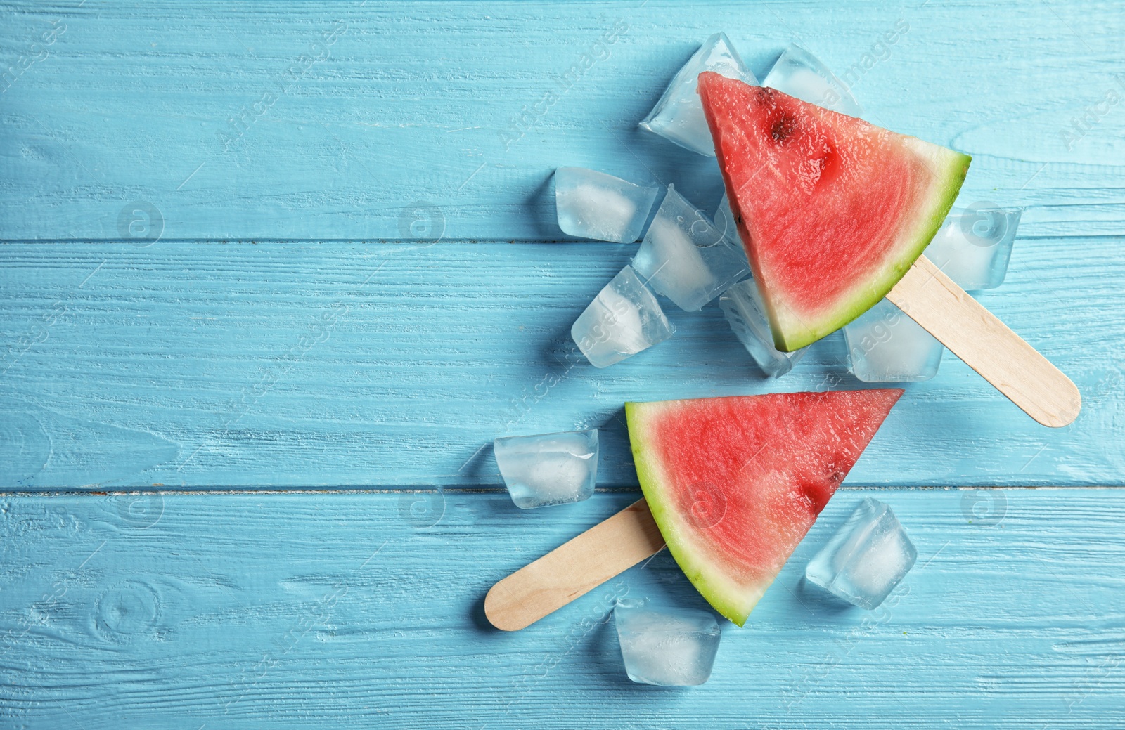 Photo of Flat lay composition with watermelon popsicles and ice cubes on wooden background