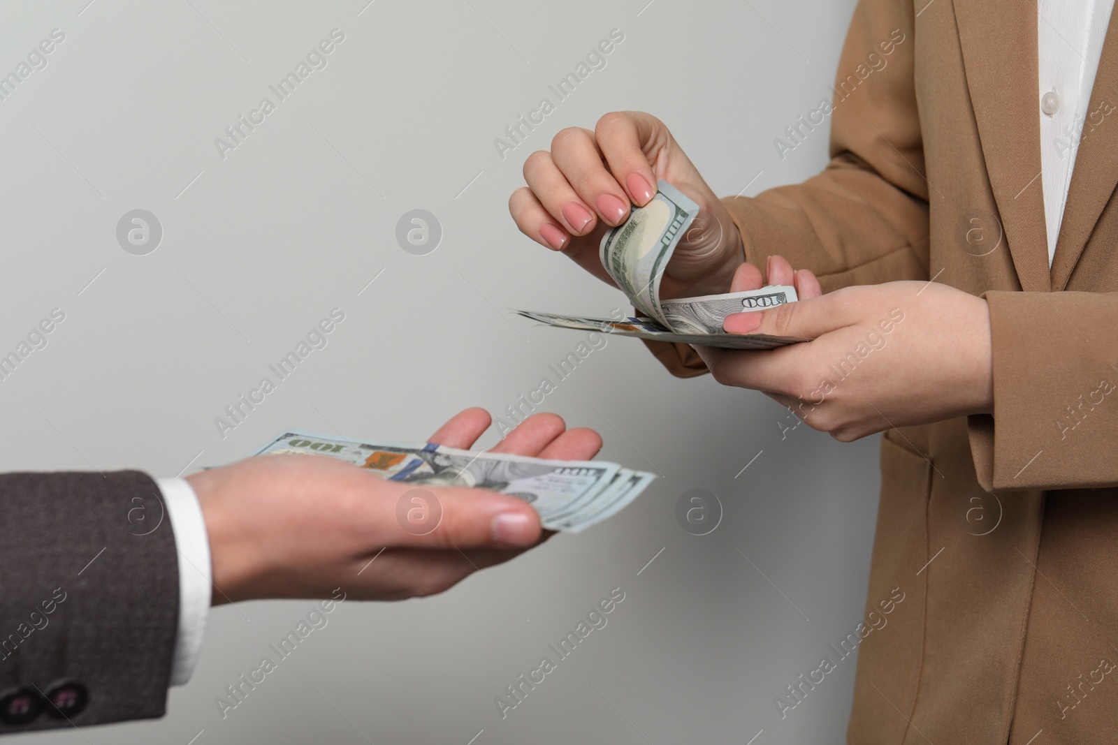 Photo of Woman giving money to man on light grey background, closeup. Currency exchange