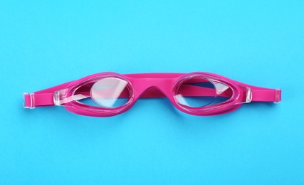 Photo of Swimming goggles on blue background, top view