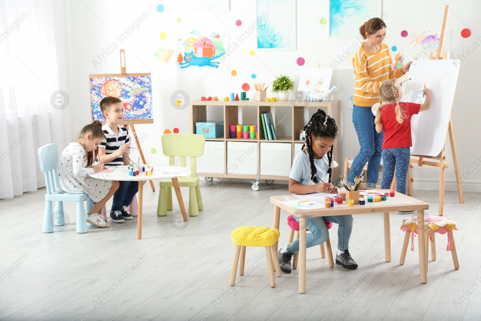 Photo of Children with female teacher at painting lesson indoors