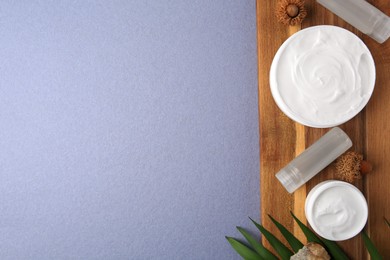 Photo of Jars of cream, shampoo samples, stone and green leaf on light blue background, top view. Space for text