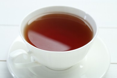 Aromatic tea in cup on white table, closeup