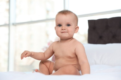 Photo of Cute baby in diaper on bed at home