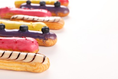 Photo of Delicious eclairs covered with glaze on white background, closeup