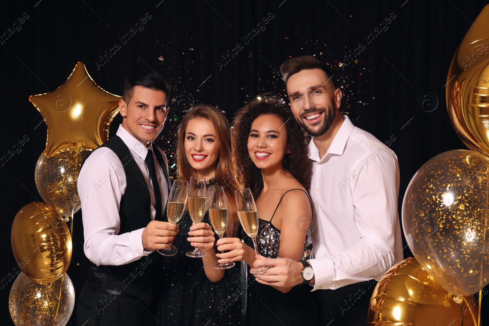 Photo of Happy friends with glasses of sparkling wine celebrating New Year on black background