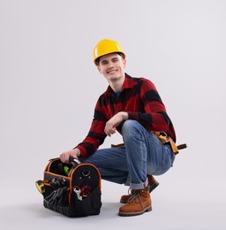 Photo of Professional repairman with tool box on light grey background. Space for text