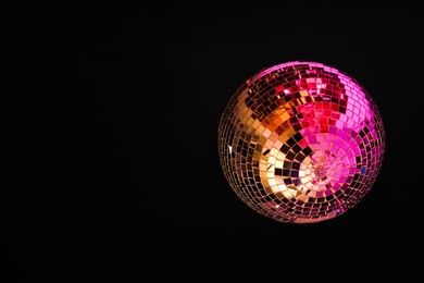 Photo of Shiny disco ball hanging on dark ceiling, bottom view