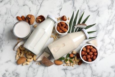 Photo of Vegan milk and different nuts on white marble table, flat lay