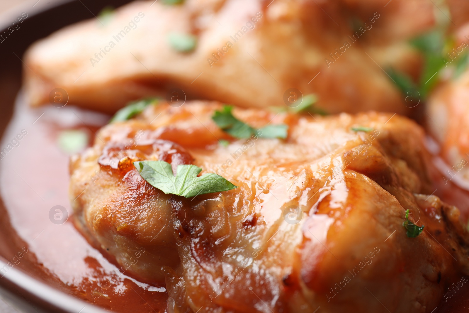 Photo of Tasty cooked rabbit meat with sauce and parsley, closeup